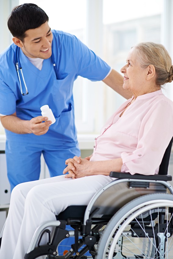 Male nurse giving medicine to senior patient on wheelchair