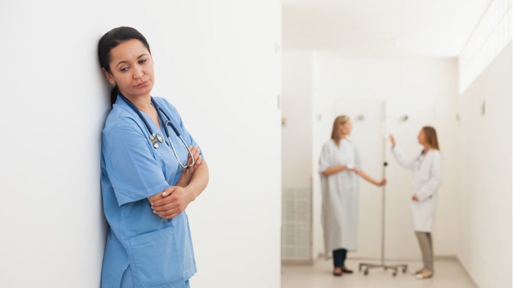 nurse feeling sad with doctor and patient in background